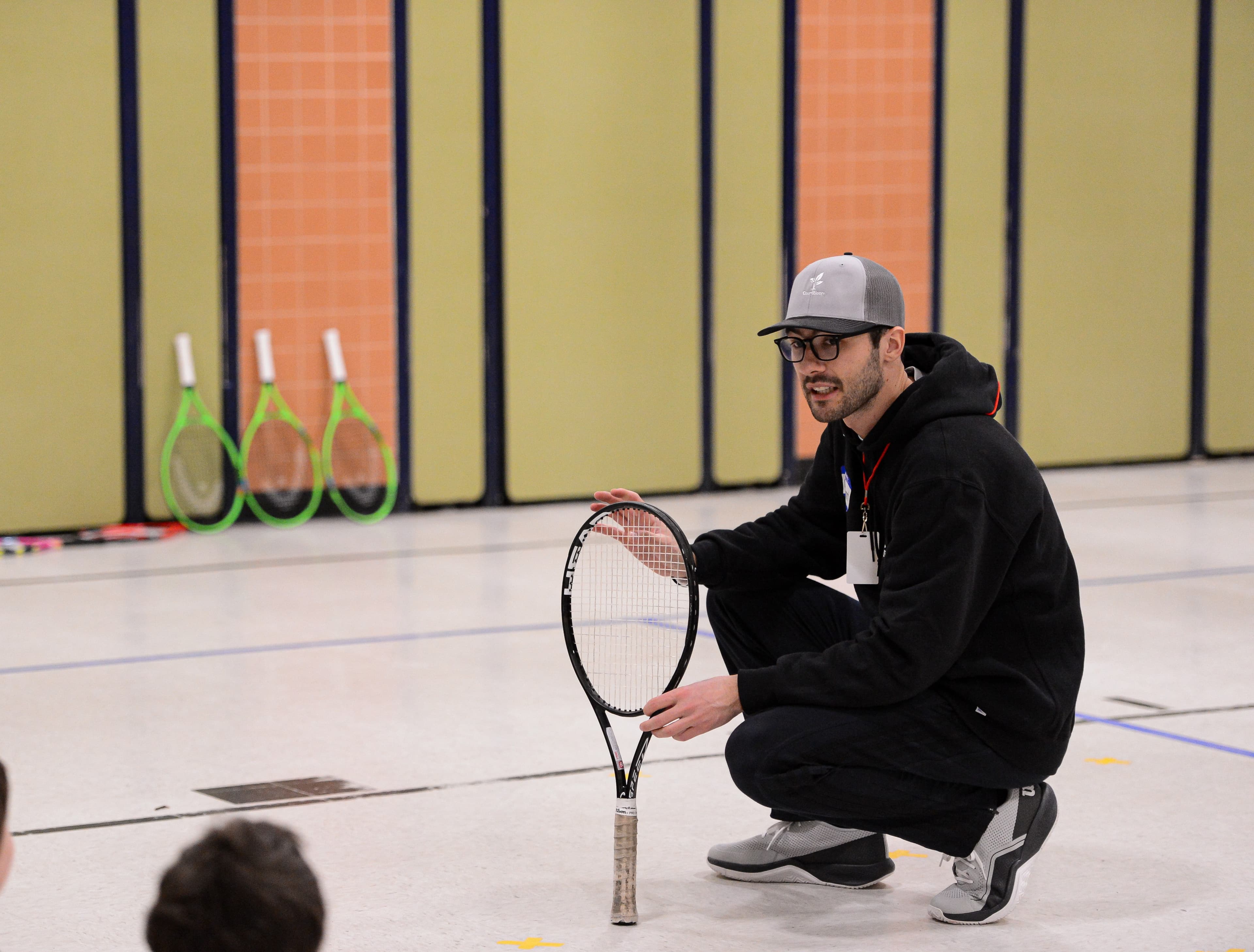 CourtBloom youth tennis photo — coach crouch